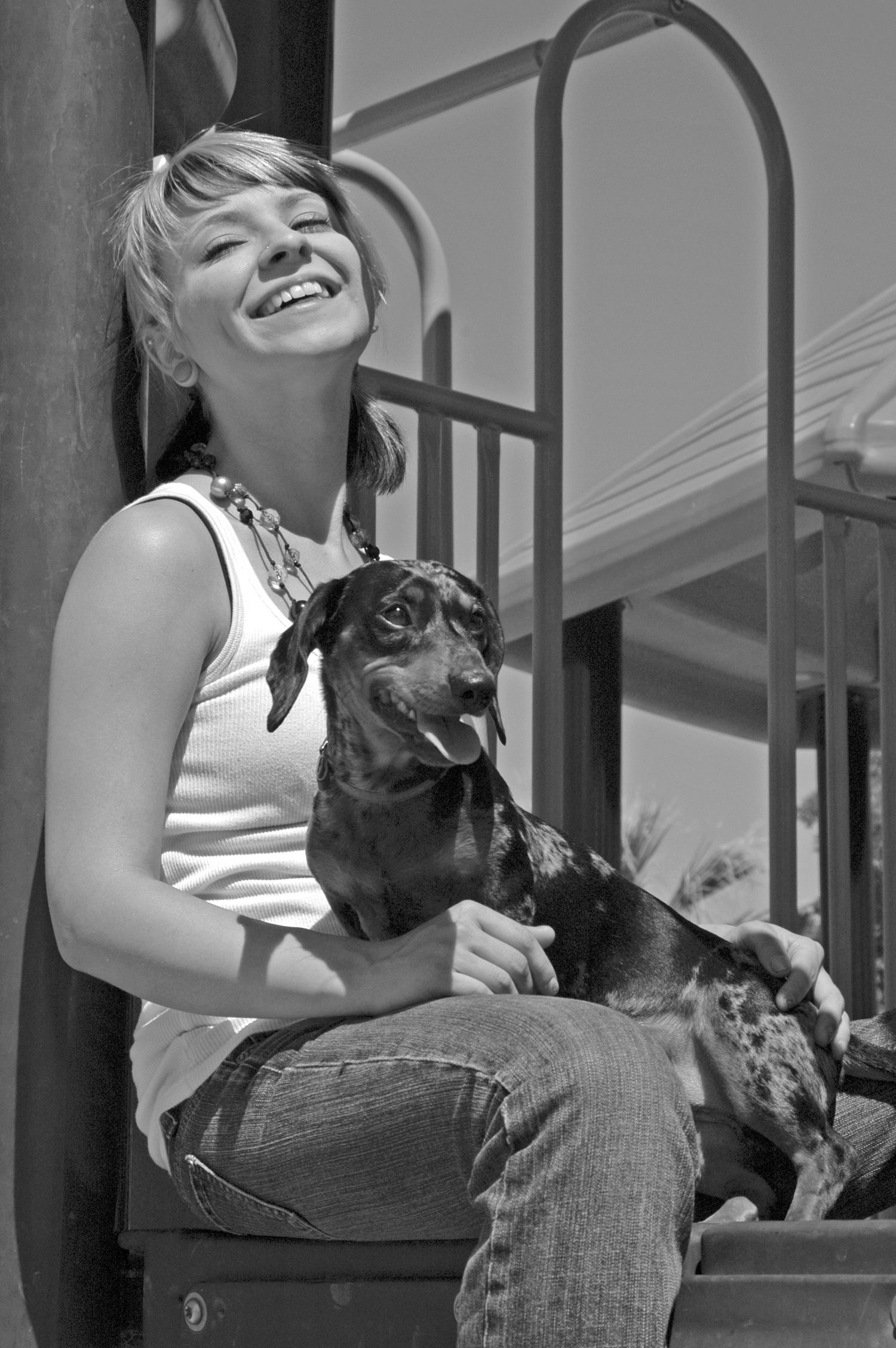 black and white candid portrait of a young lady and her dapple dachshund