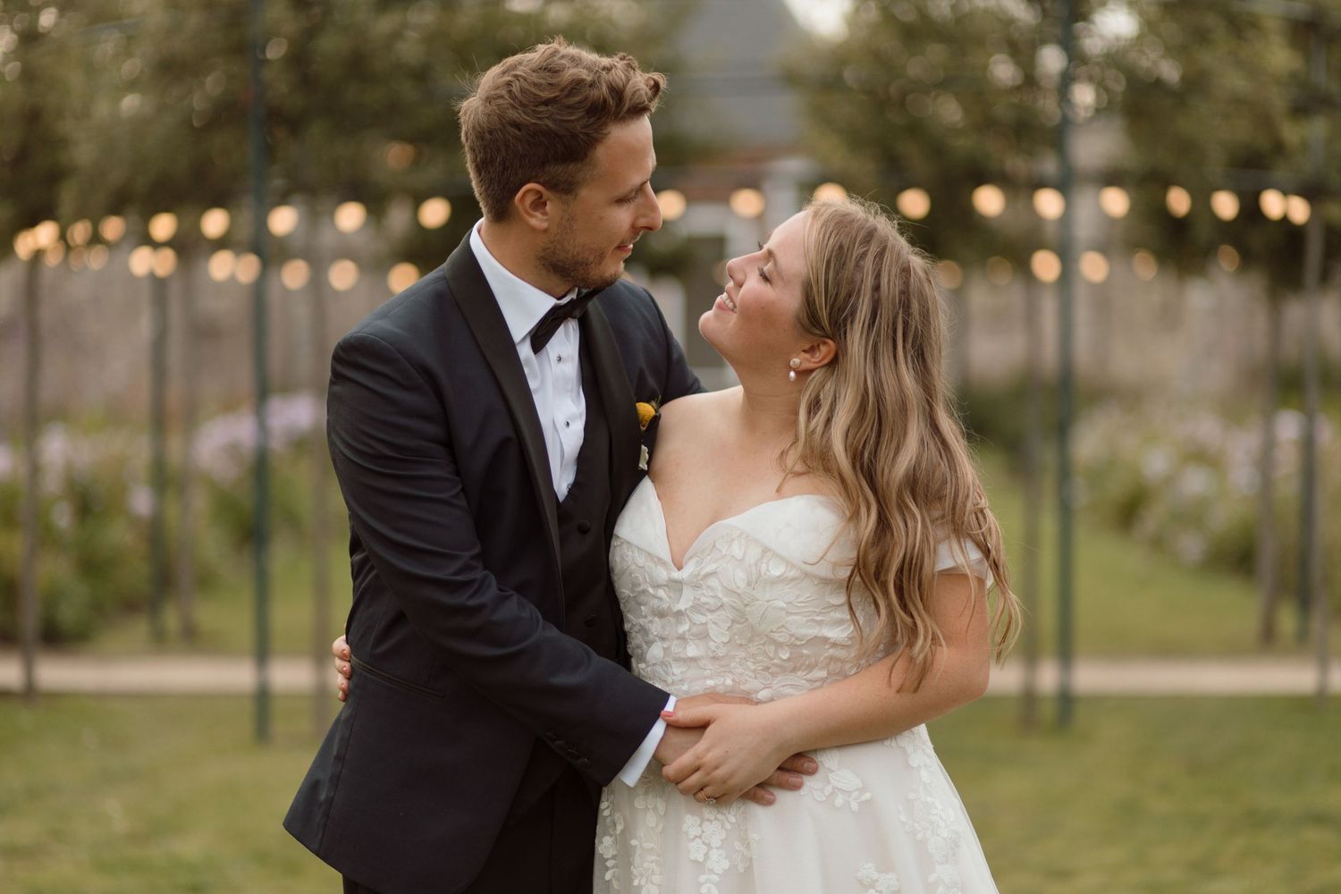A Bride and Groom looking lovingly at each in an embrace with festoon lighting lit up behind them at Gileston Manor, Barry in South Wales.