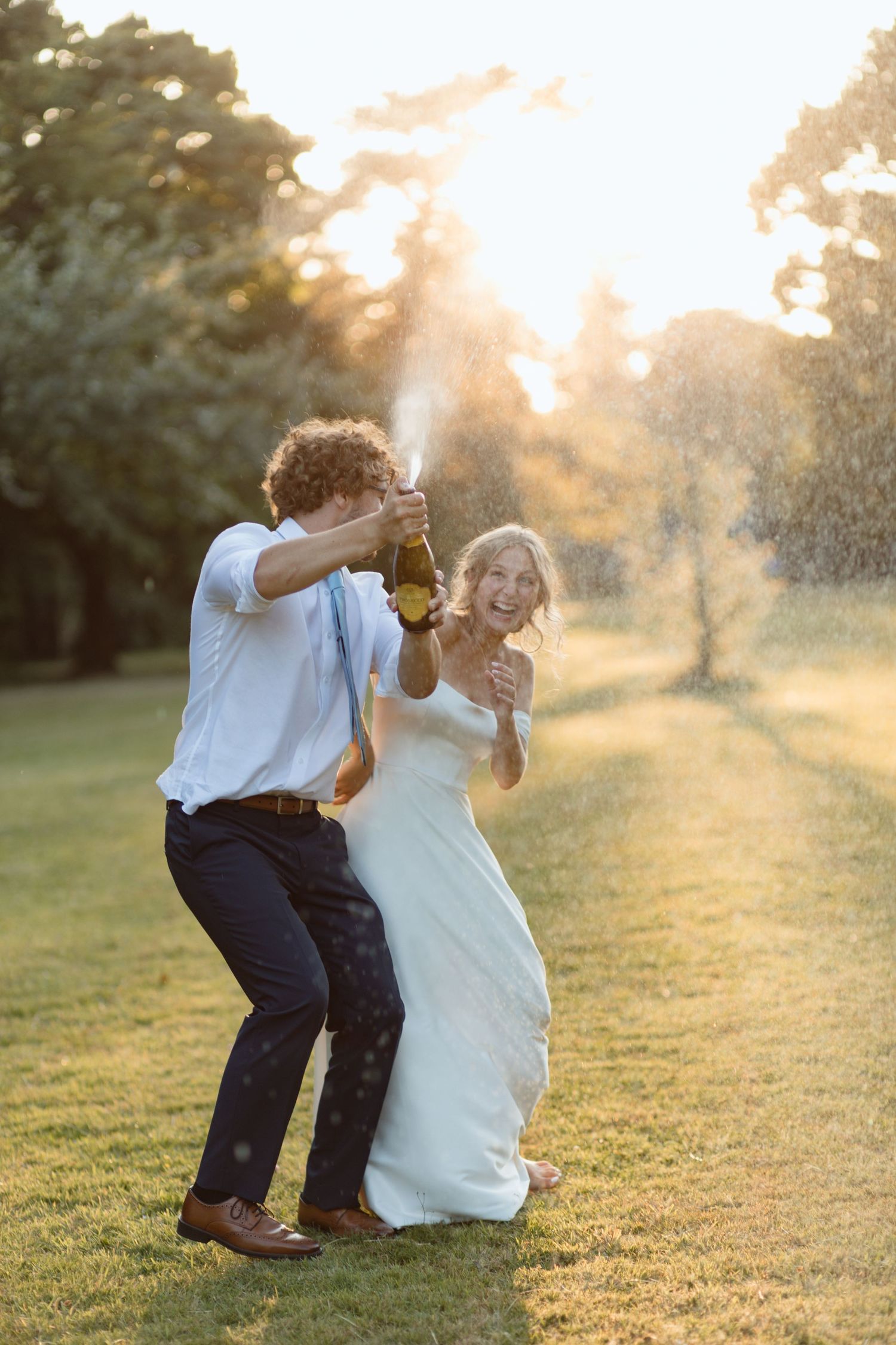 Bride & Groom pop a bottle of champagne at sunset. The bride is laughing because her husband got quite excited with the bubbly.