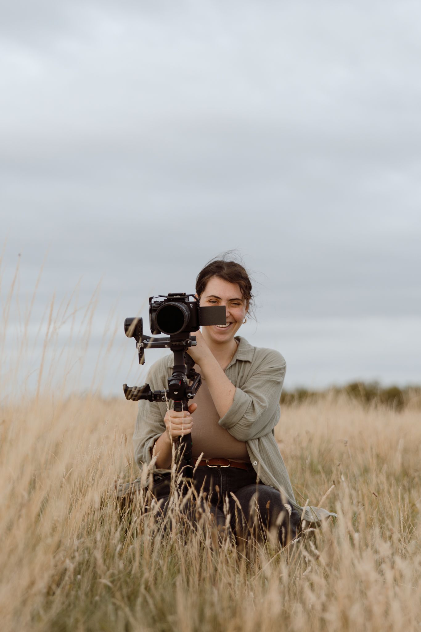 South Wales Wedding Videographer Bri is crouching while filming on a Sony A7siii with a Ronin RS3Pro gimbal at Southerndown South Wales.