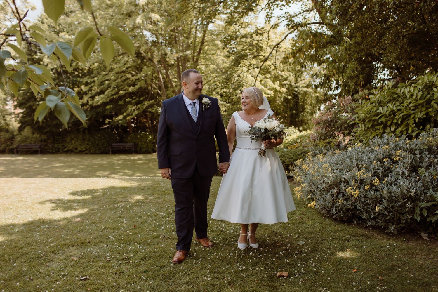Bride & Groom walking in the shade smiling at each other straight after their ceremony at the Mansion House Registry Office in Newport.