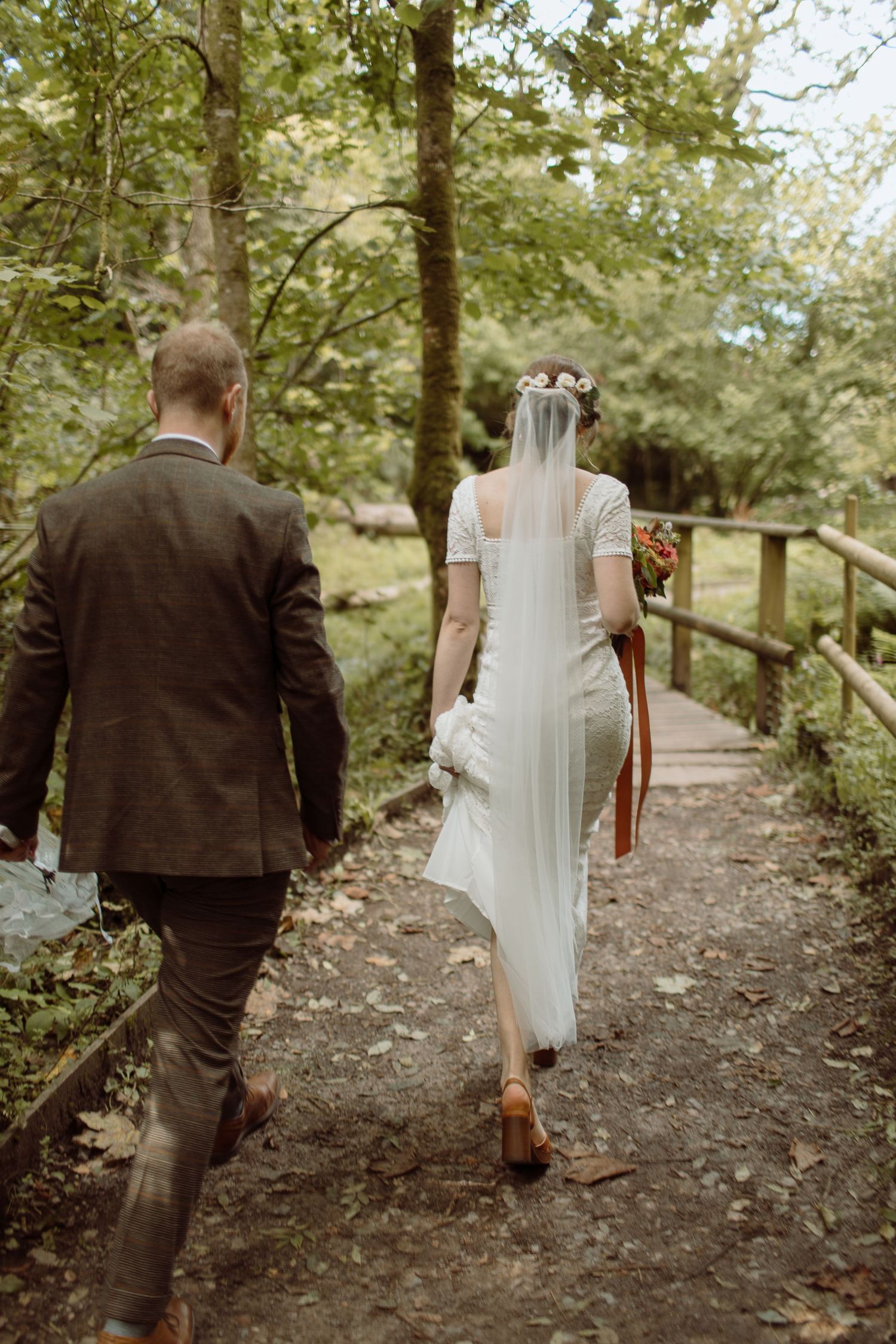 Bride & Groom walking along a dirt path at Bryngarw Country Park in Bridgend on their wedding.