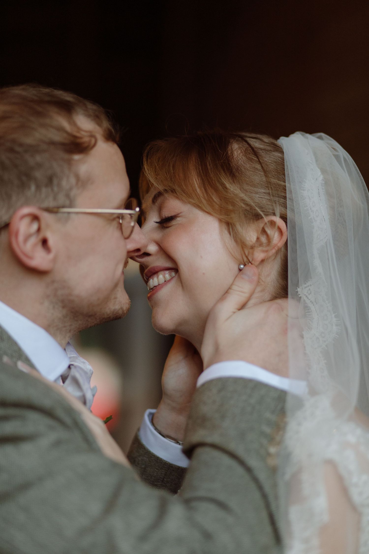Bride & groom about to kiss sheltering from the rain under the barn entrance at Upwaltham Barns, Southampton.