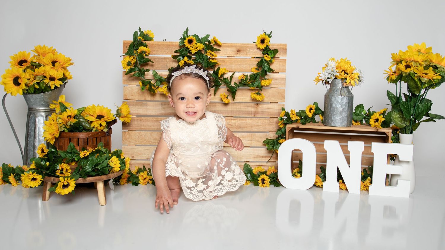 Baby photography setup with sunflowers and rustic wooden backdrop.