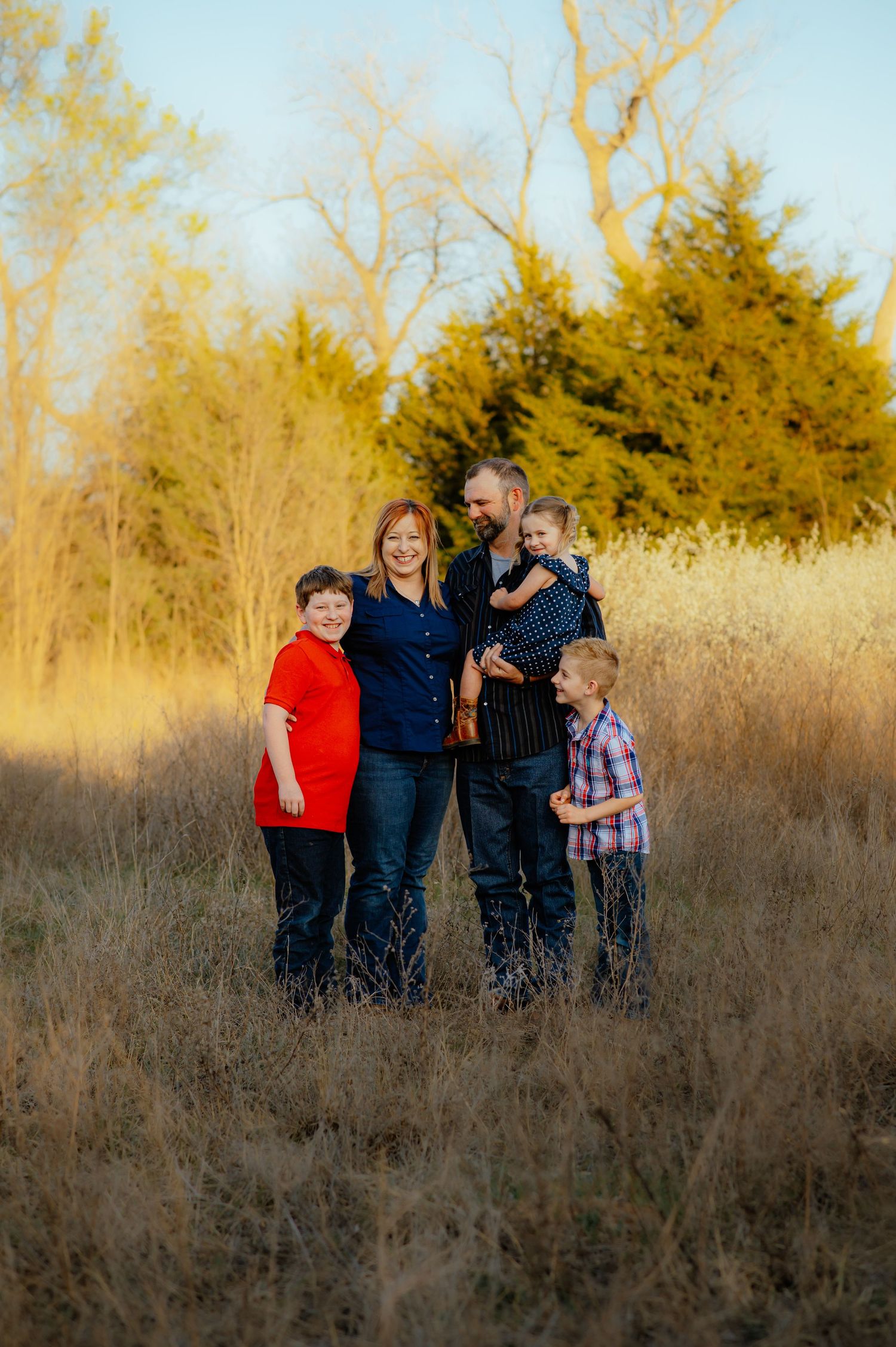 Family snuggled together during golden hour session in a field near Enid, Oklahoma, captured by family photographer Taryn Elizabeth.