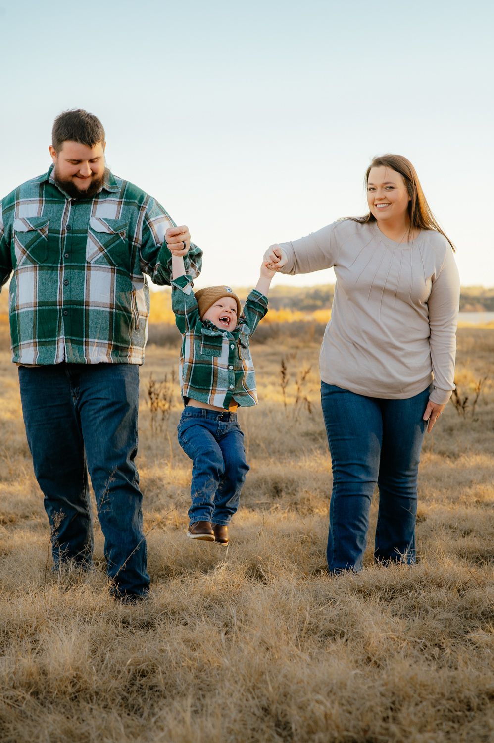 Mom and dad swinging their toddler during an Enid family photos session at the Great Salt Plains Lake in Oklahoma.