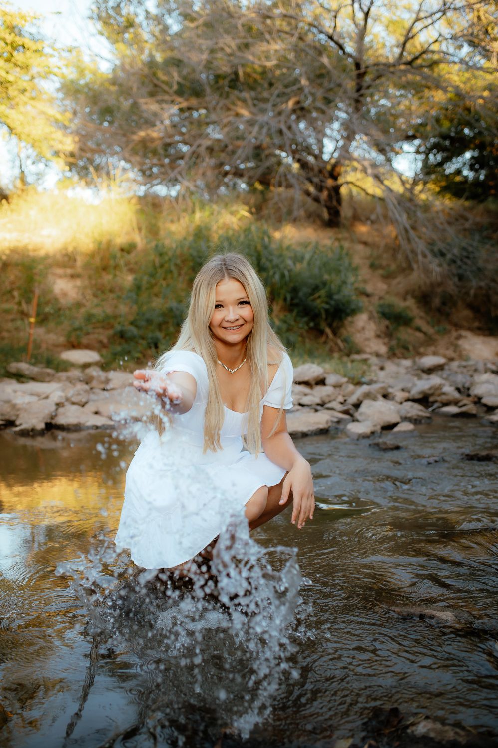 Girl posing in a creek for her senior photos with a Enid Senior Photographer.