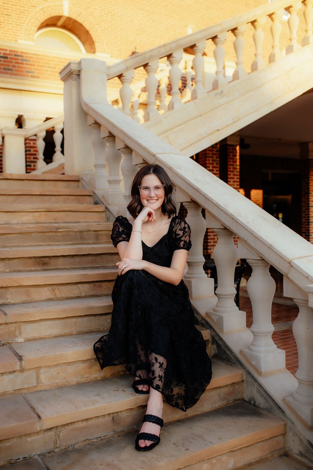 College graduate sitting on stairs at Oklahoma State University with an Enid Senior Photographer.