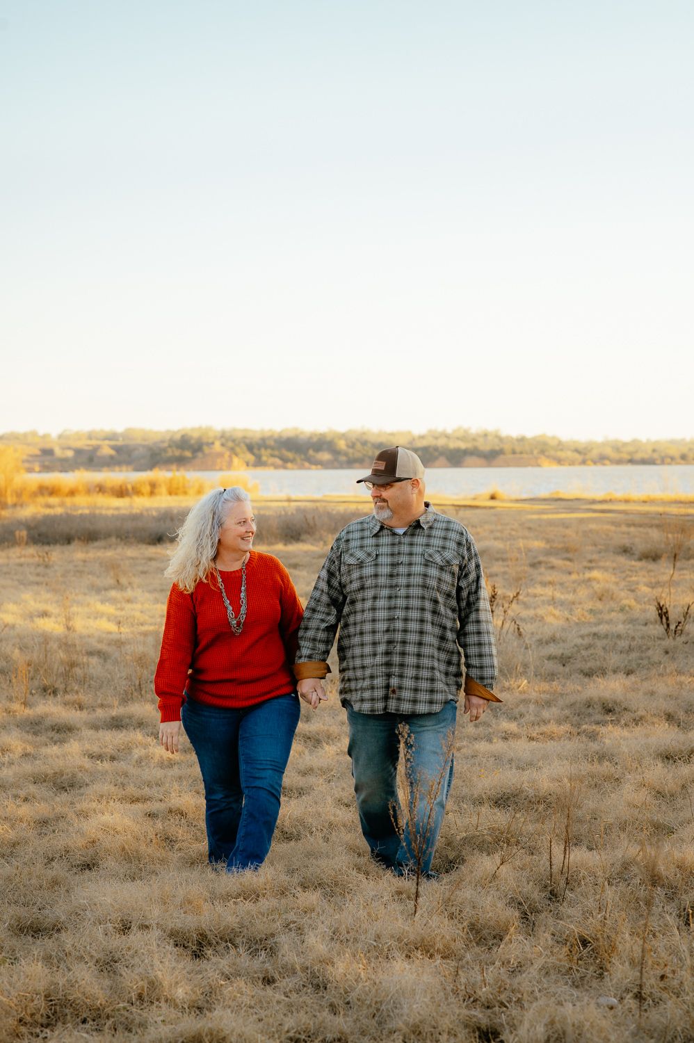 Husband and wife smiling and walking with each other by the Great Salt Plains Lake for Enid Oklahoma family photos.