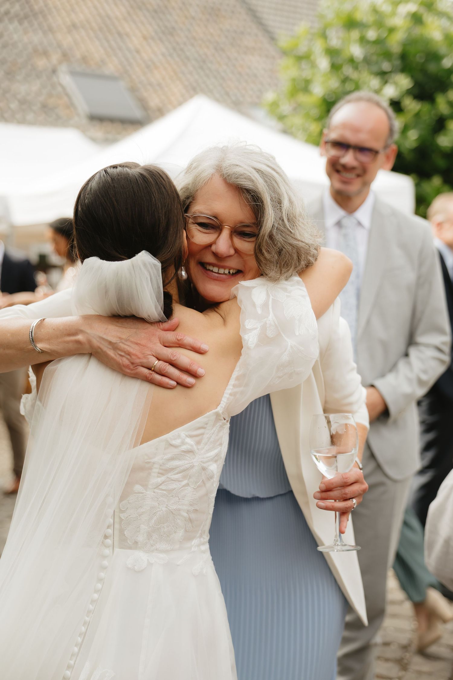 Wedding guests share emotional embraces with the bride in white dress.