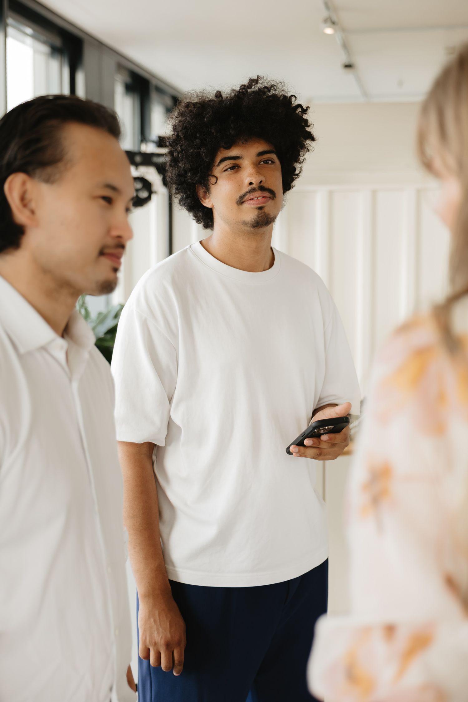 A series of candid shots showing people in white shirts interacting in a bright indoor space.
