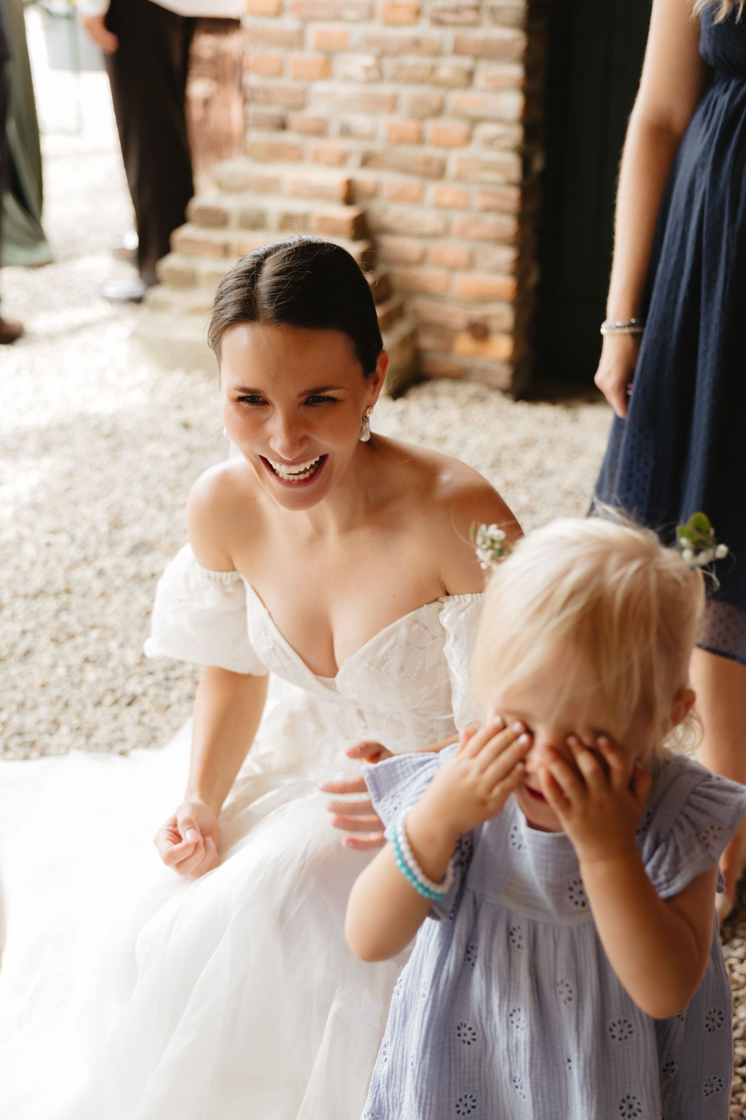 Bride in white dress sharing sweet moments with young flower girl in light blue dress.