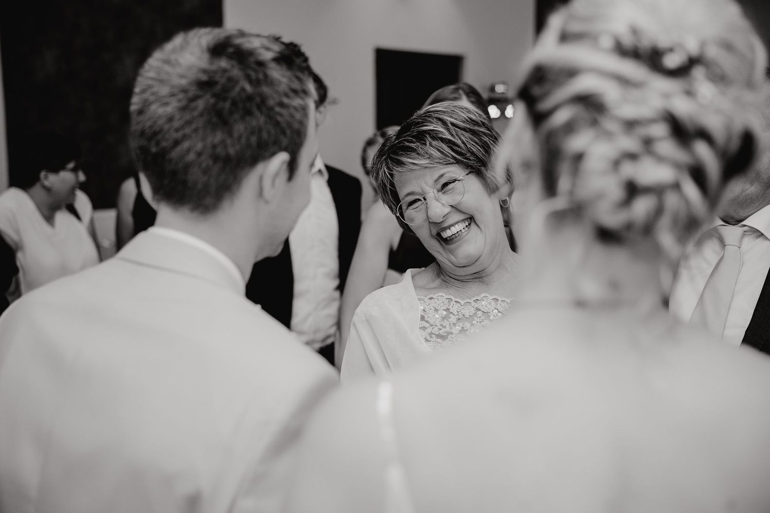 Wedding guests share joyful laughter and candid moments during an outdoor celebration.