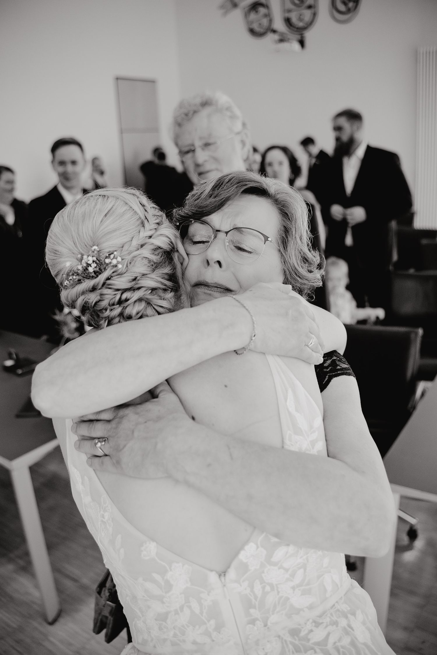 Black and white photo sequence showing a tender emotional embrace between two people at what appears to be a wedding event.