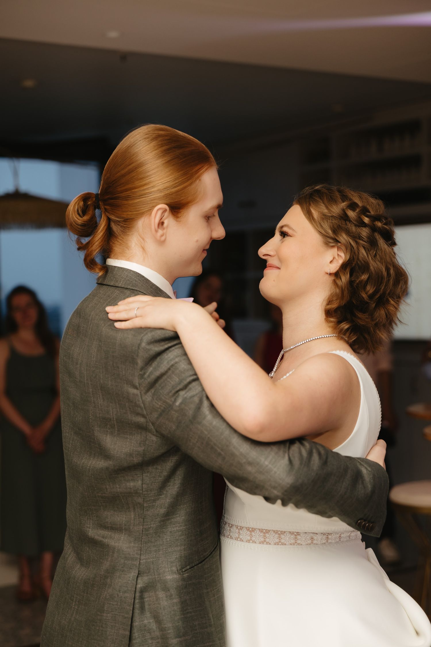 Dancing couple shares an intimate moment during their wedding dance, with the bride in white and groom in gray.