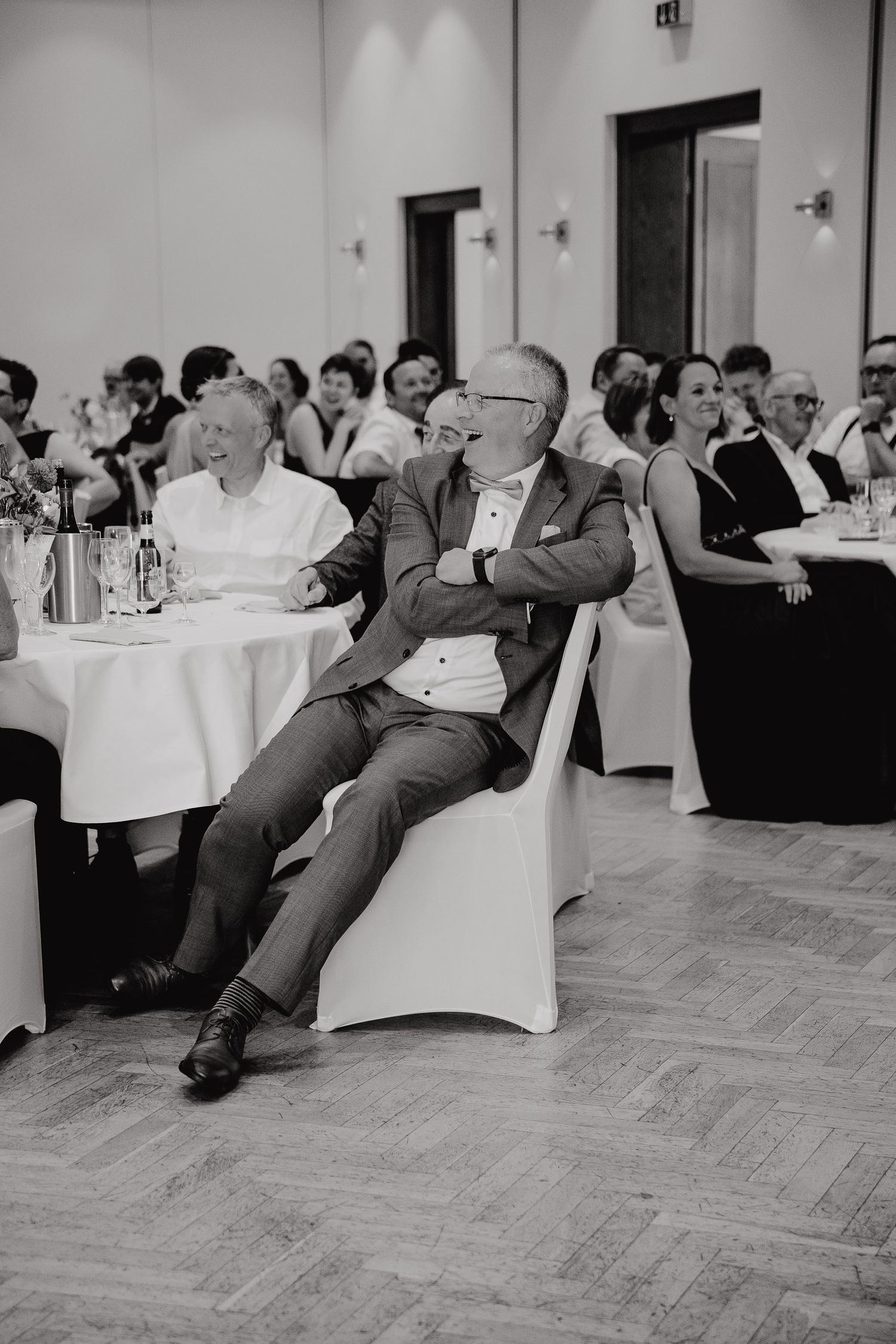 Black and white photo sequence showing a person falling backwards off a chair at a formal event with tables.