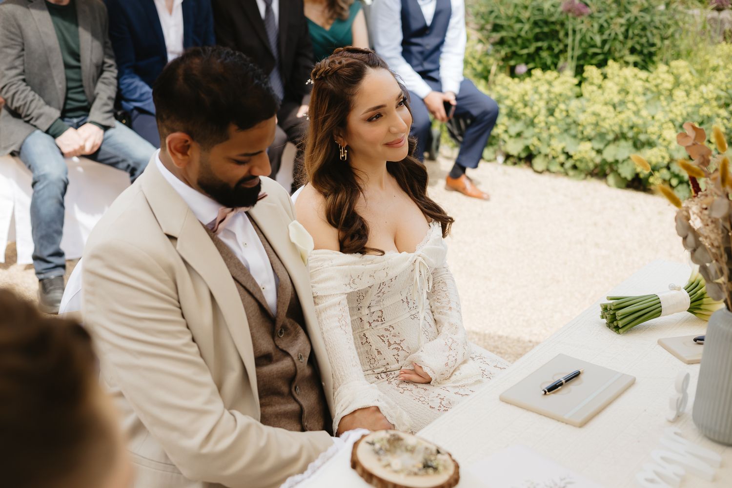 Couple shares joyful moment during outdoor wedding ceremony under white umbrellas.