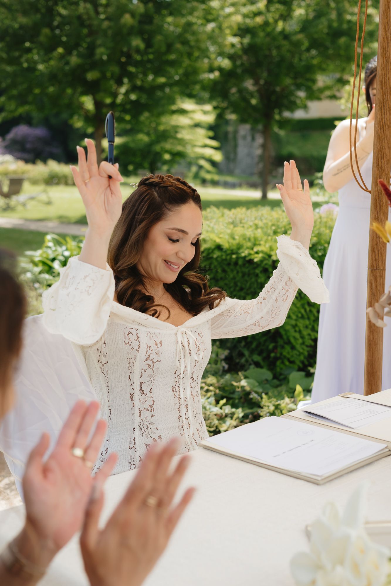 Wedding celebration with raised hands and joyful expressions during an outdoor ceremony.
