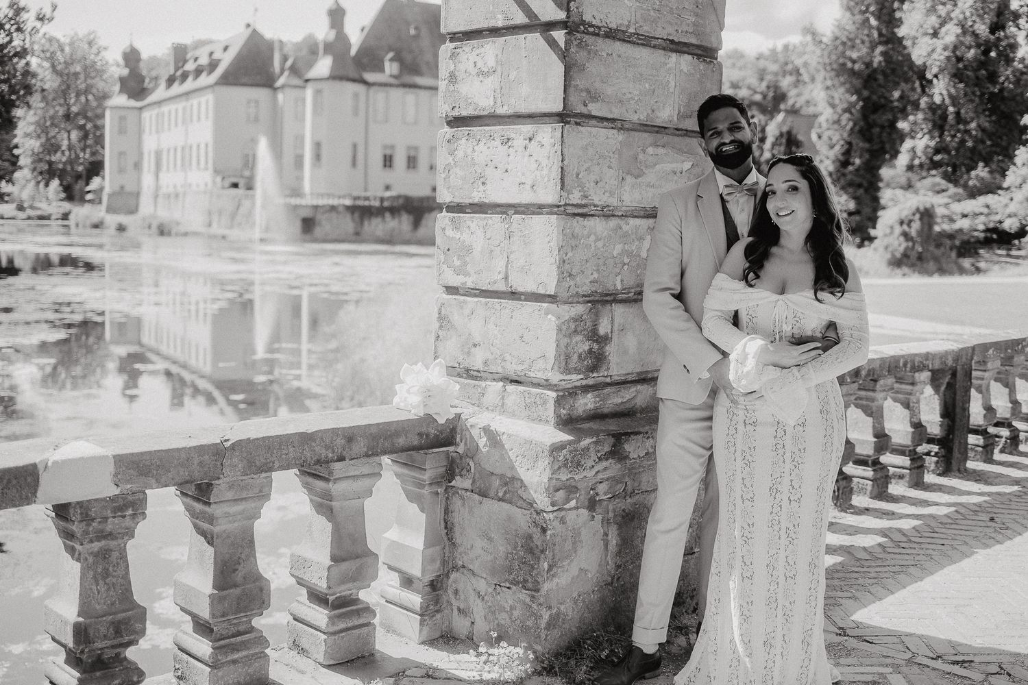 Wedding couple poses under stone archway of historic building.