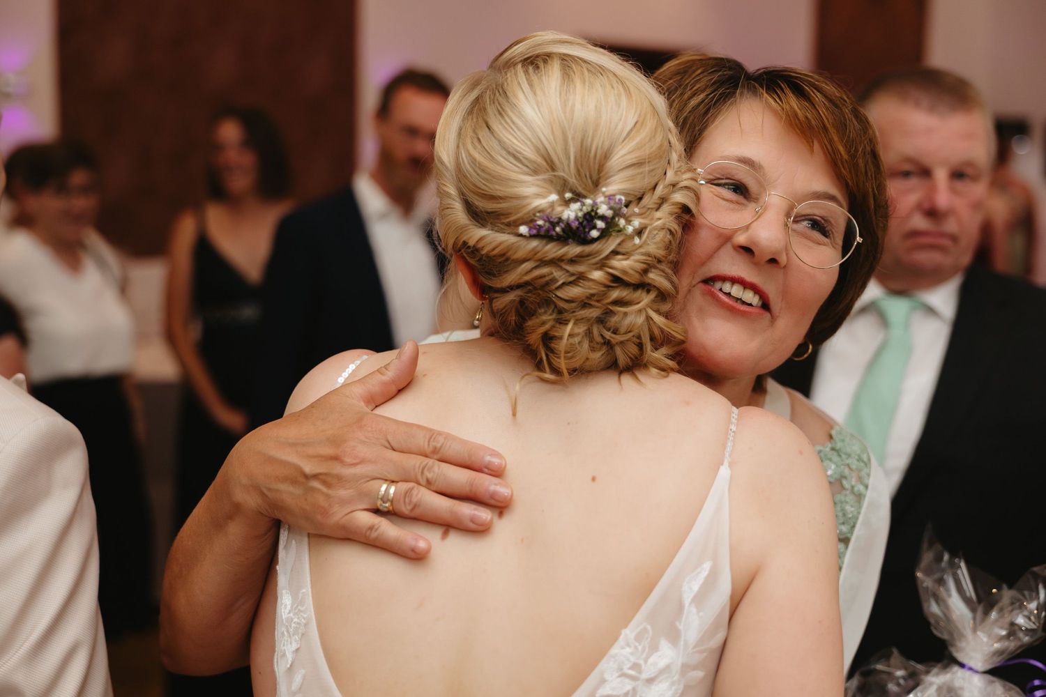A couple shares an intimate dance moment at their wedding reception while guests look on from the background.
