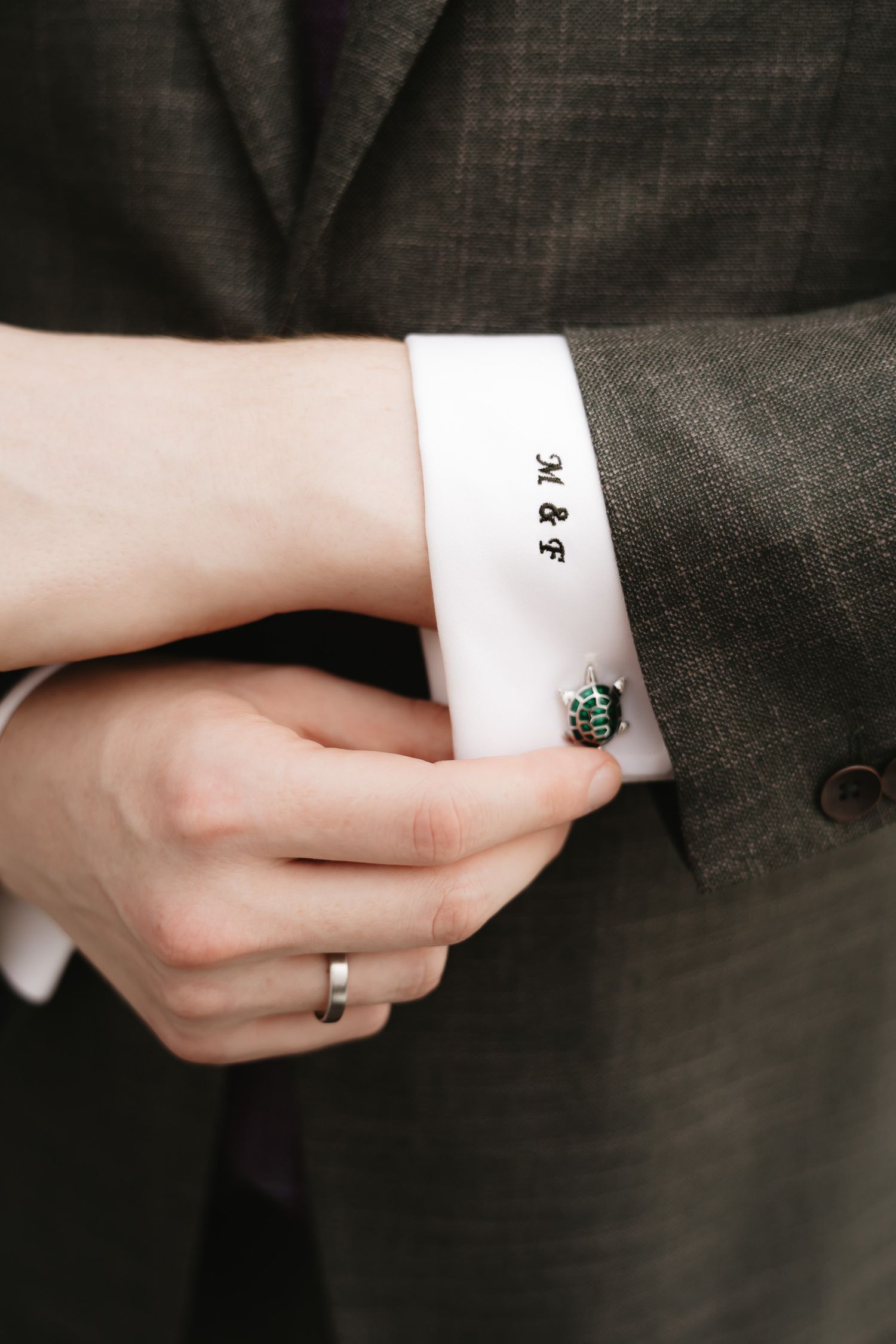 A sequence of hands adjusting white cuffs and sleeve buttons on a dark suit jacket.