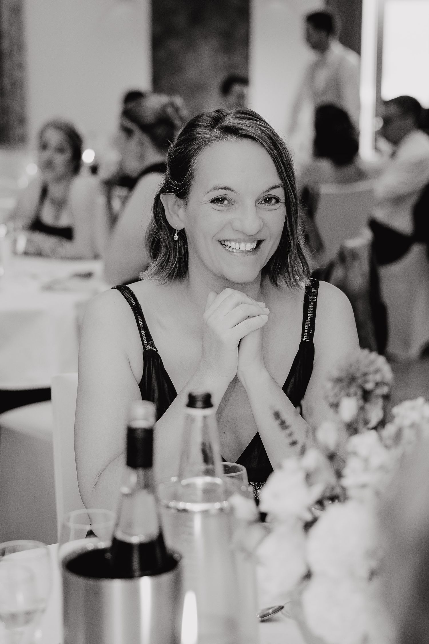 A sequence of black and white candid photos showing someone laughing and smiling at a dining table.