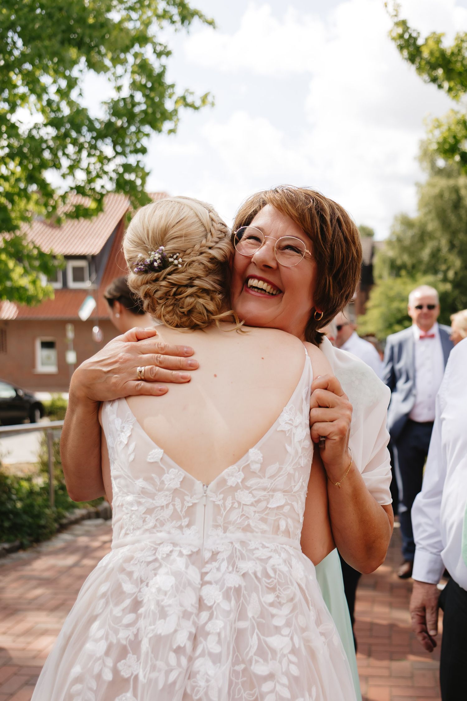 A sequence of joyful hugs and embraces at an outdoor wedding celebration.