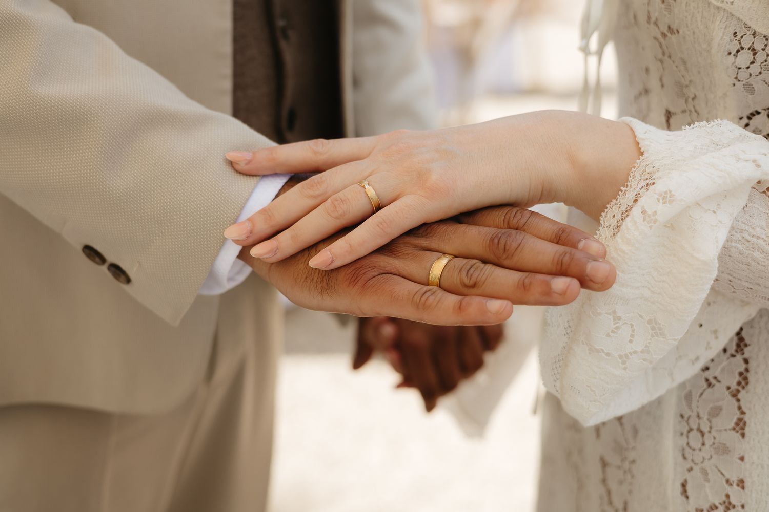 Close-up details of hands during wedding ring exchange ceremony.