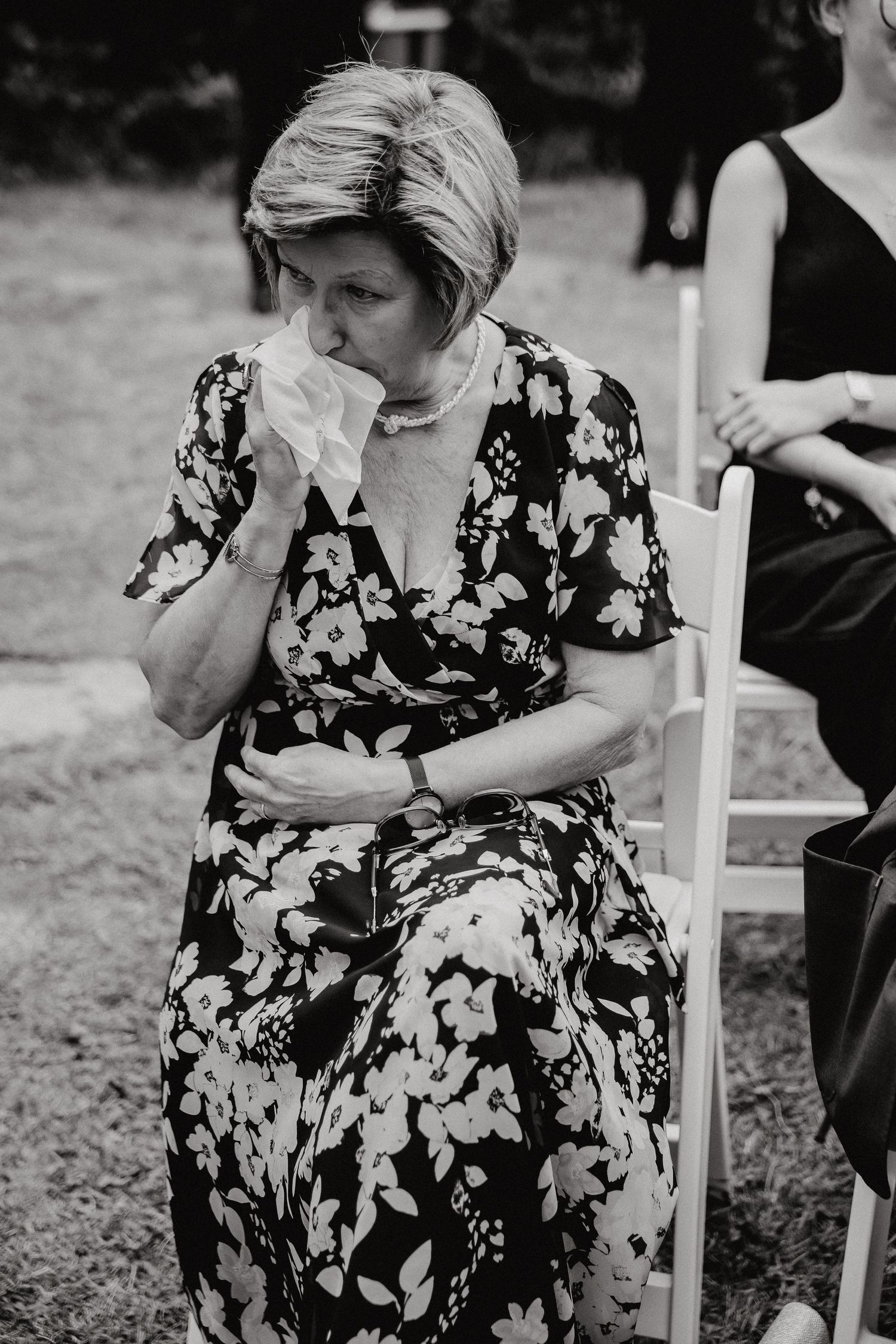 Guest in floral dress showing emotional reaction during wedding ceremony.