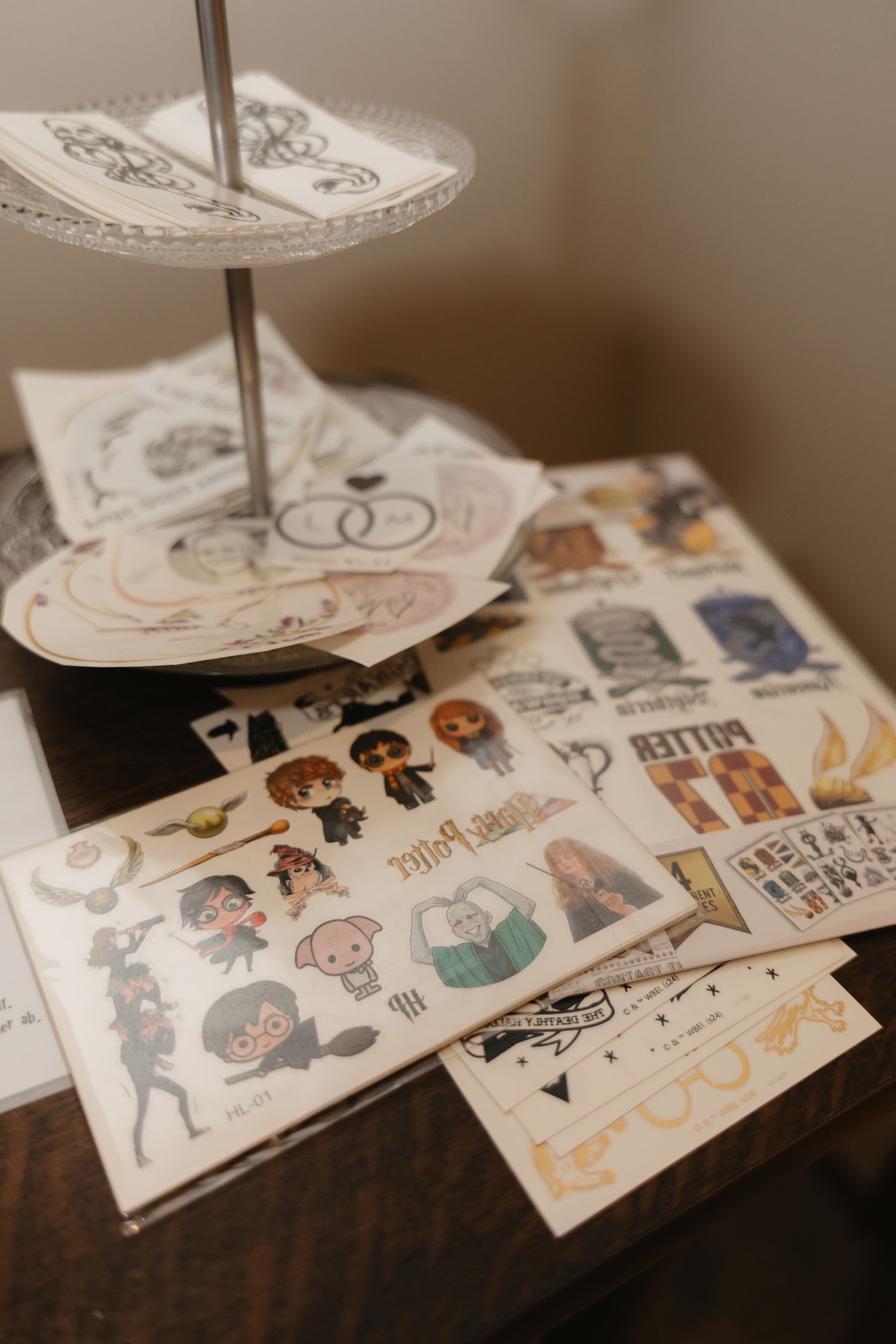 Close-up view of Harry Potter themed stickers or temporary tattoos arranged in a decorative display on a dark wooden surface.