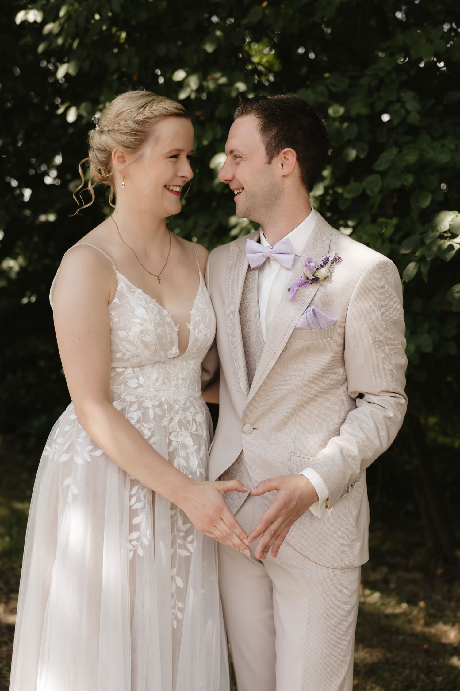 A couple shares a joyful moment on their wedding day wearing light colored formal attire and floral accents.