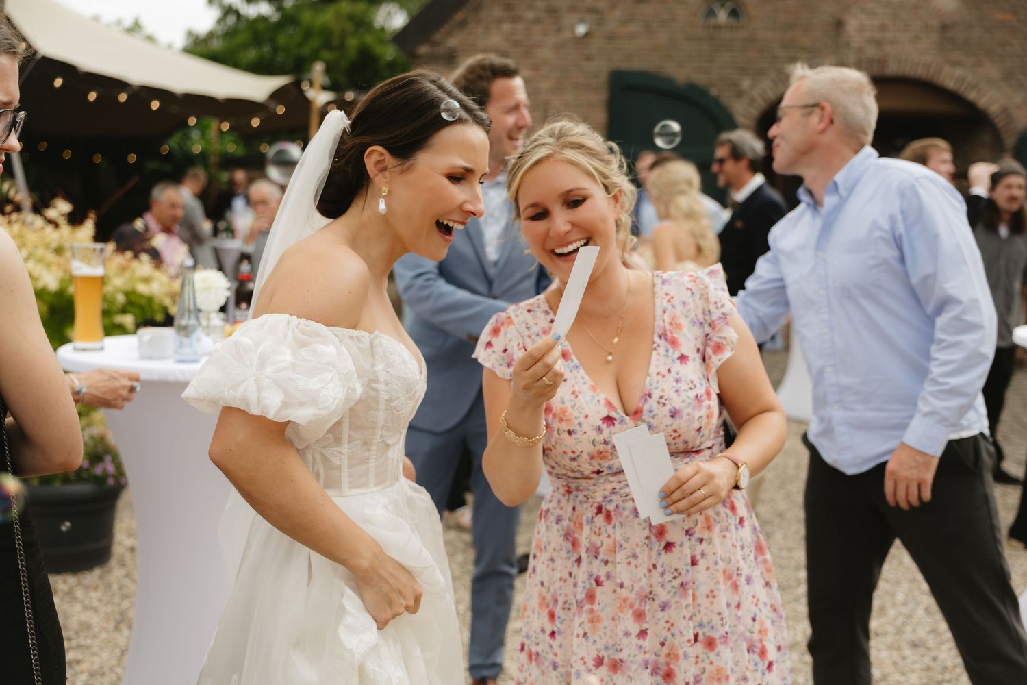 Joyful outdoor wedding celebration with guests in floral dresses.