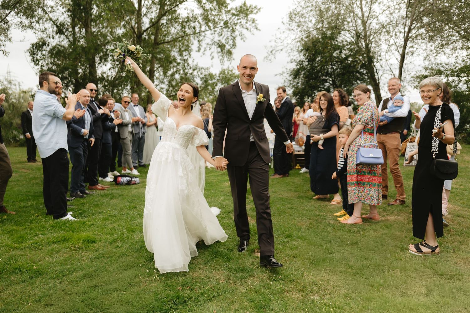 Wedding celebration on a green lawn with guests watching the couple dance.