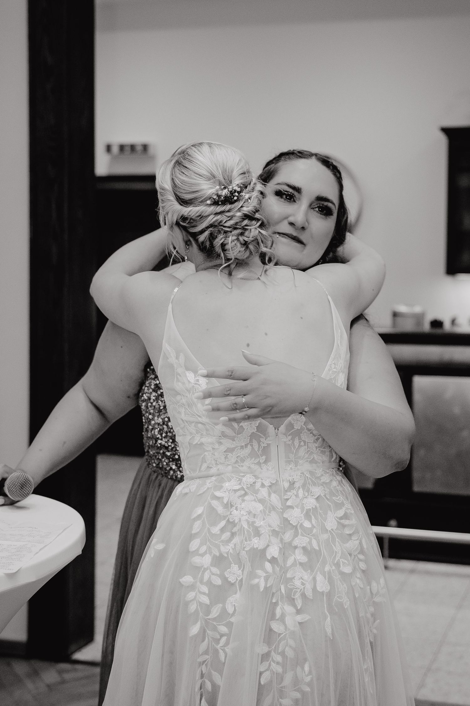 A series of black and white photos showing someone getting dressed in a delicate white lace wedding gown.