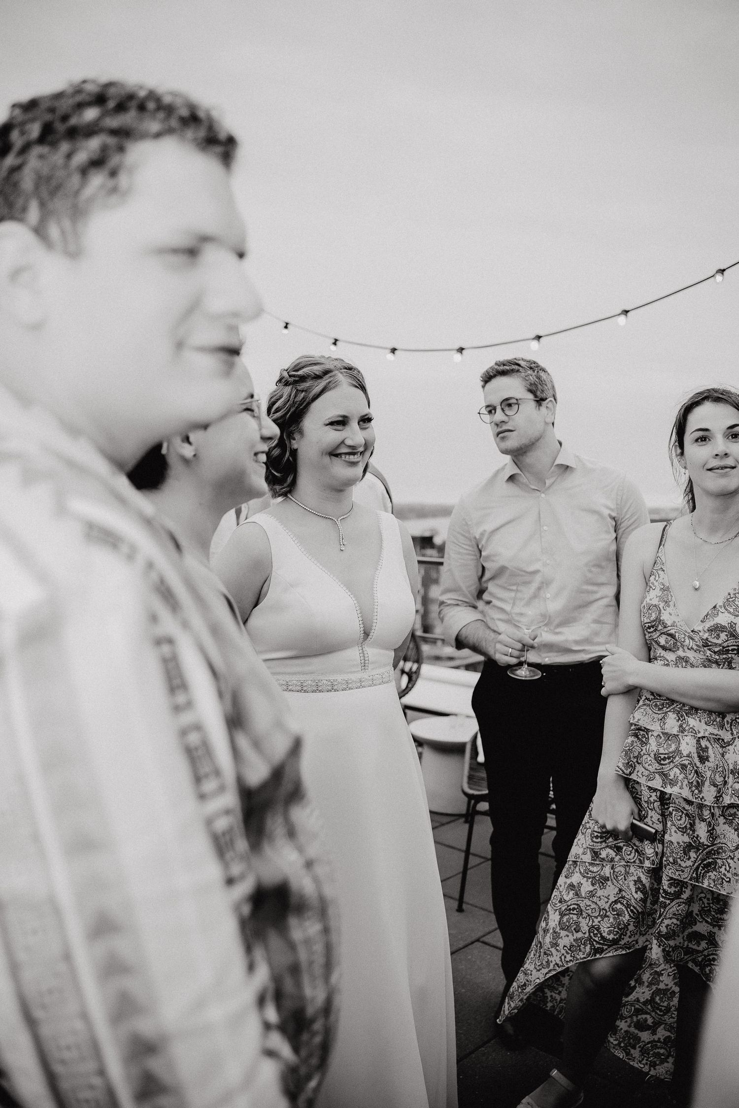 Black and white photo sequence shows people engaged in casual conversation at an outdoor gathering.