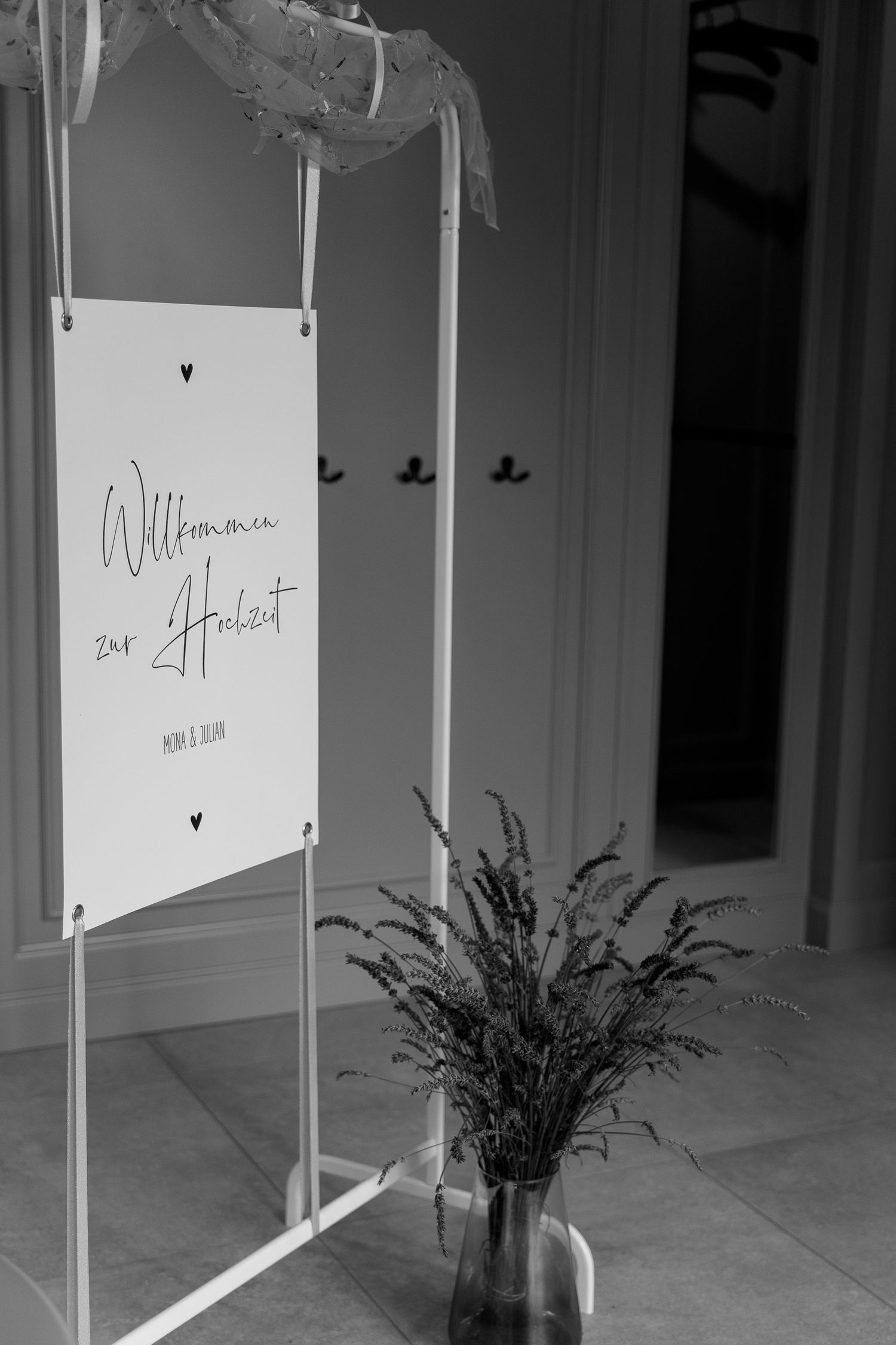White welcome signs and decorative elements displayed in a minimalist interior with a vase of dried flowers.