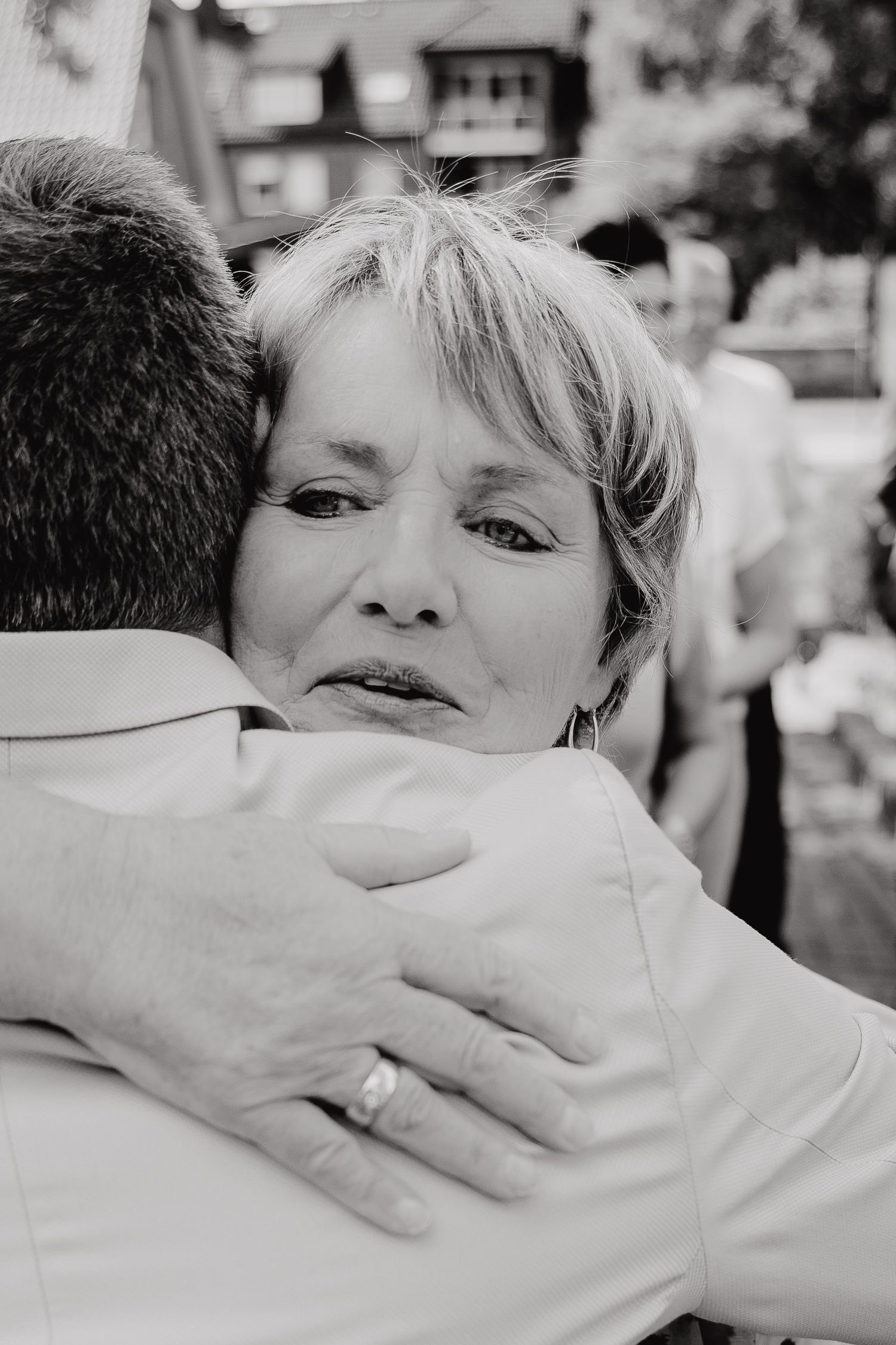 Black and white photos capturing emotional embraces between wedding guests during a heartfelt moment.