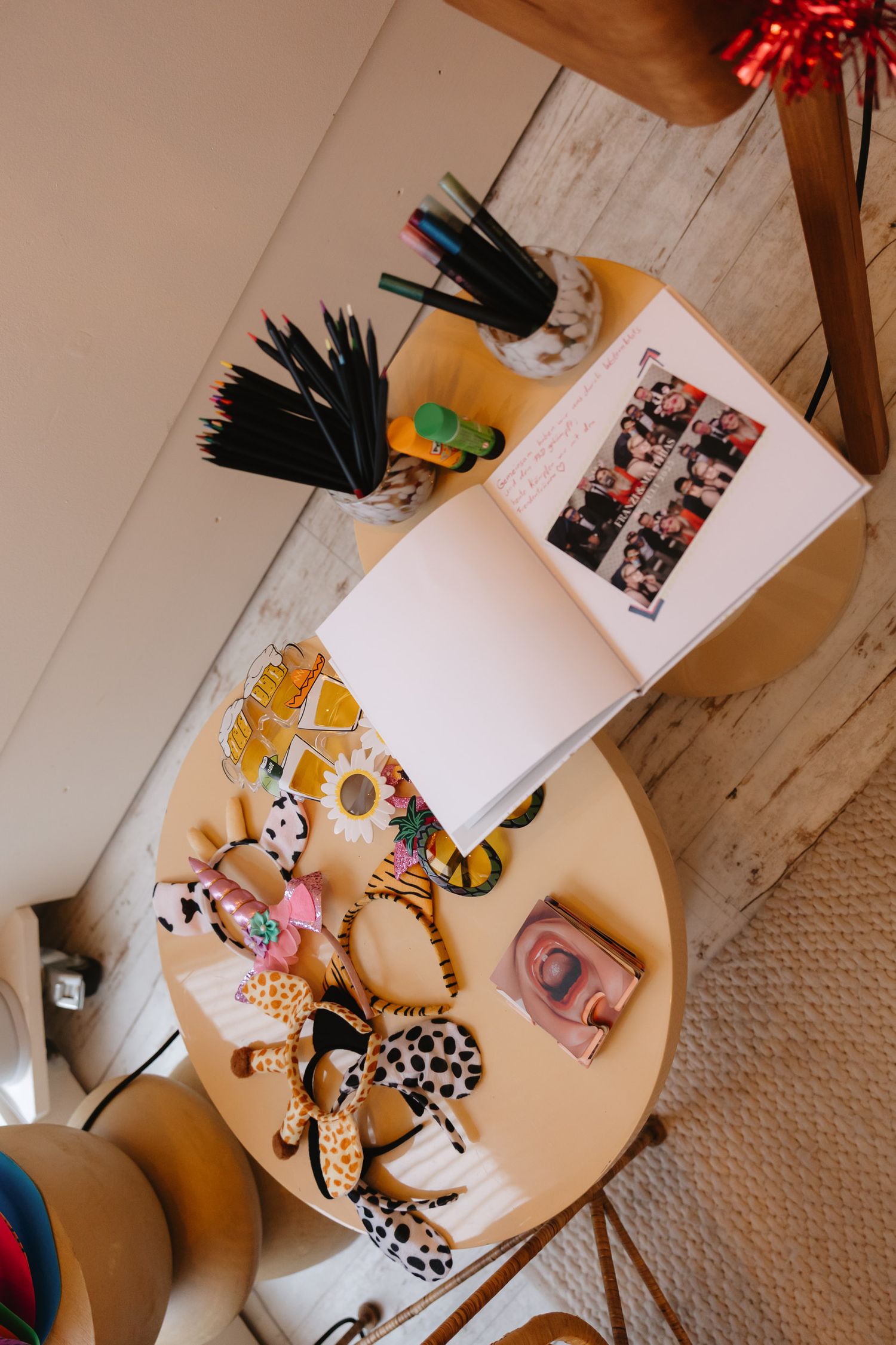 Overhead view of craft supplies and photo strips scattered on a wooden table with decorative accessories.