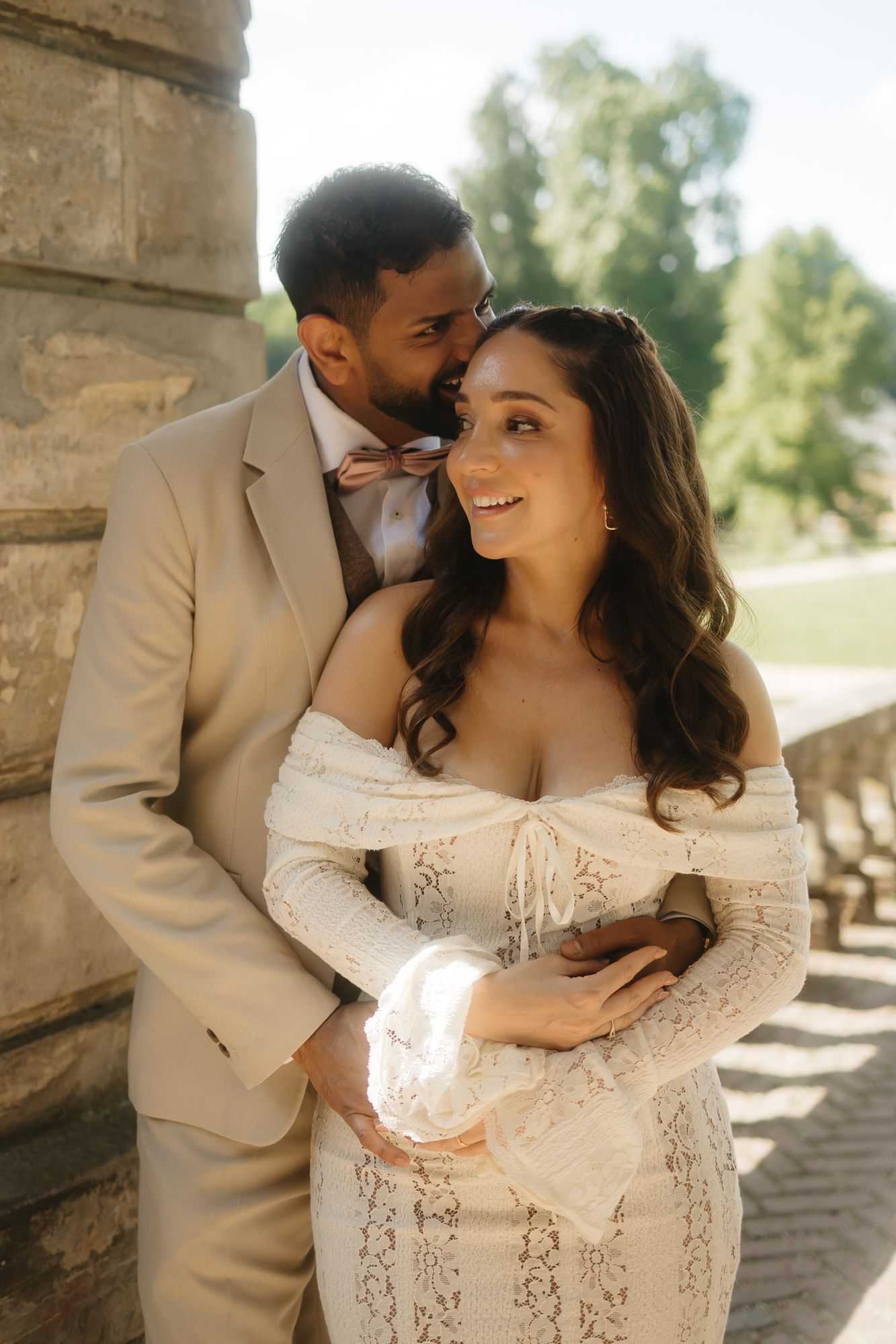 Intimate wedding portraits captured under stone archway with natural lighting.