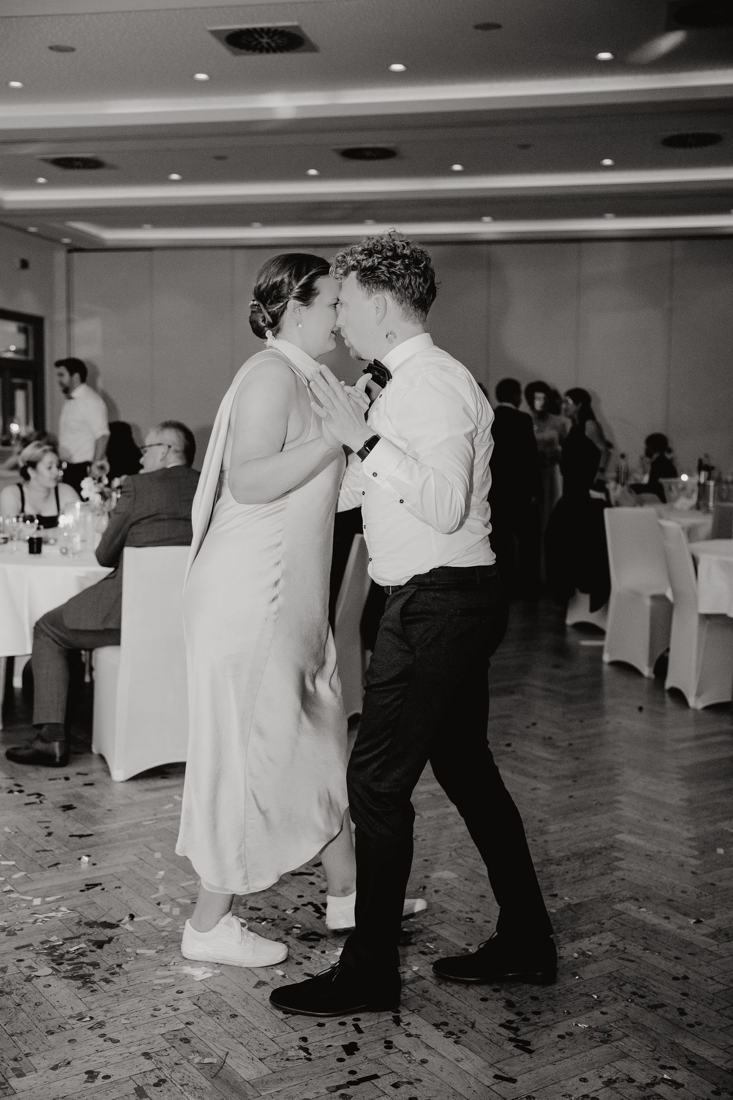 Black and white photo series of couples dancing at a wedding reception with confetti scattered on the dance floor.