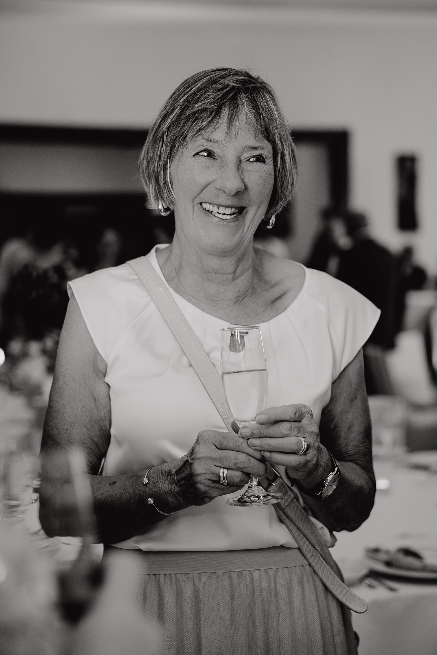 Black and white photo series showing someone in a white top holding and drinking from a teacup at a social gathering.