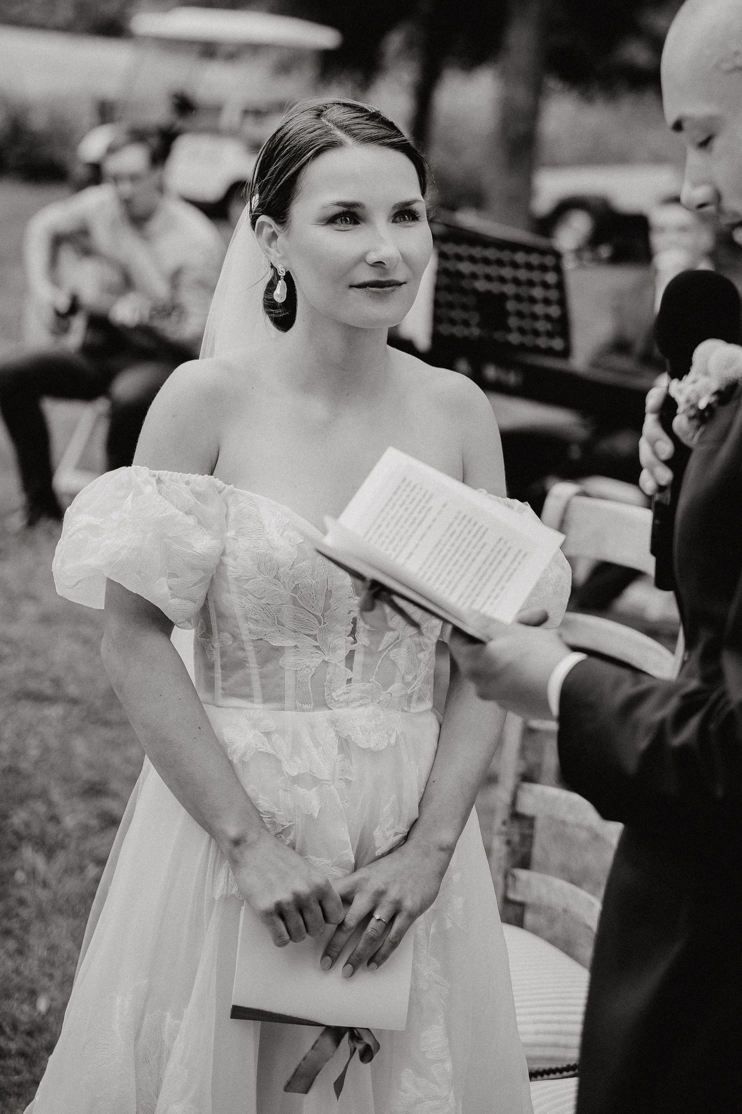 Black and white photos of bride holding papers during wedding ceremony.