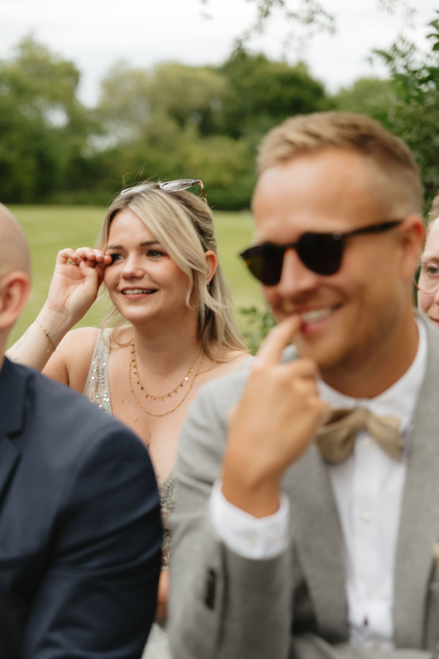 Wedding guests laughing and wiping tears during emotional ceremony moment.