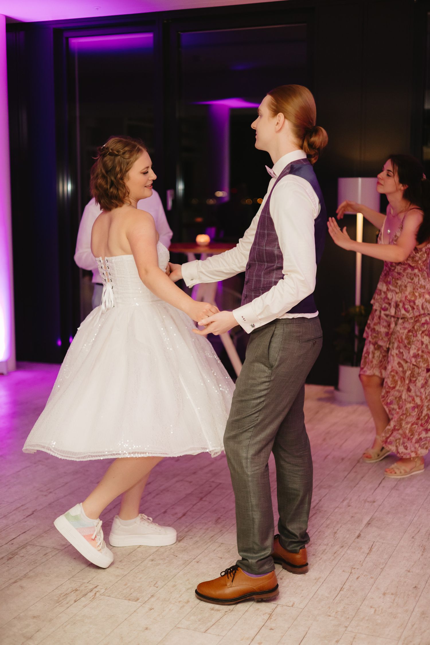 A sequence of dance photos showing a child in a white dress twirling with someone in gray pants at a wedding reception.