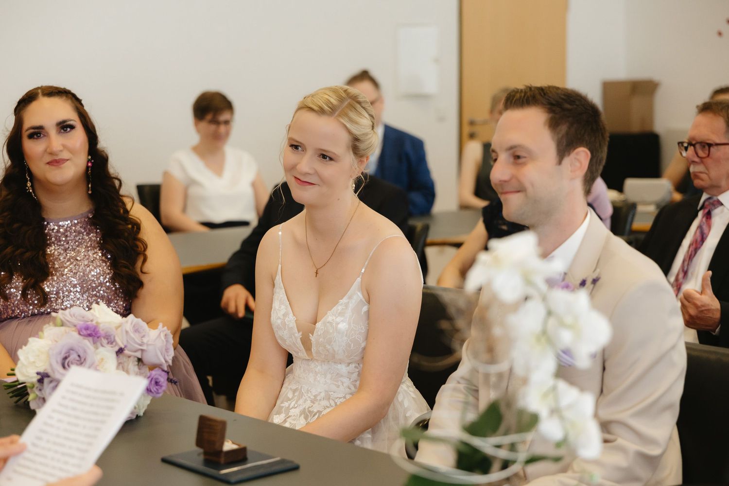 A row of wedding guests sit at a long table during a reception celebration.