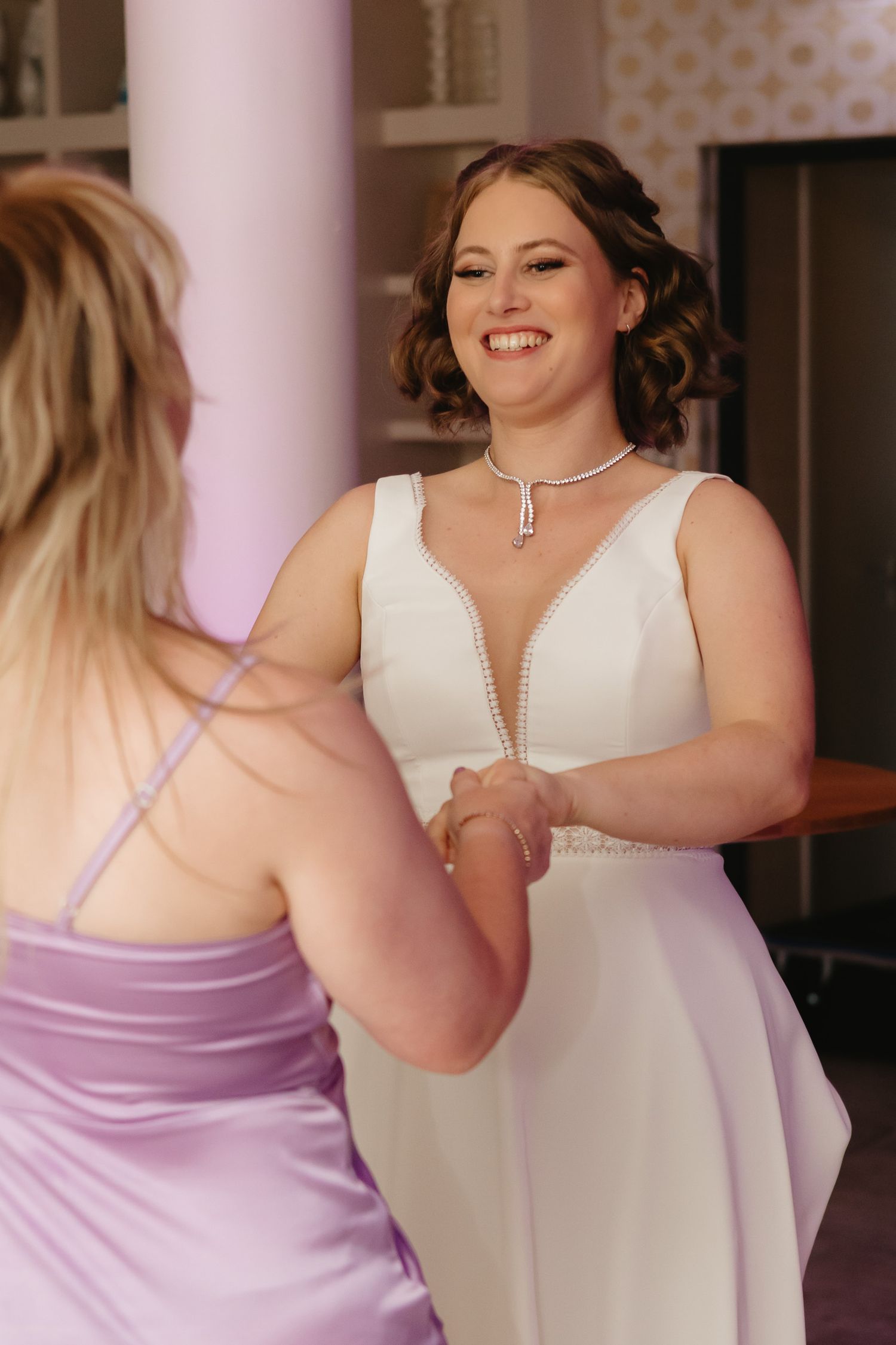 Wedding party members in lavender and white dresses dance together during a celebration.