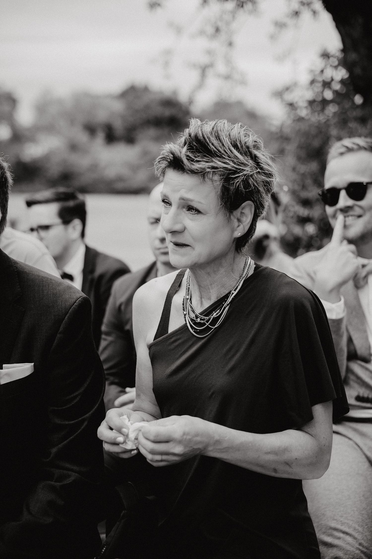 A group of wedding guests enjoying an outdoor celebration in black and white photography.