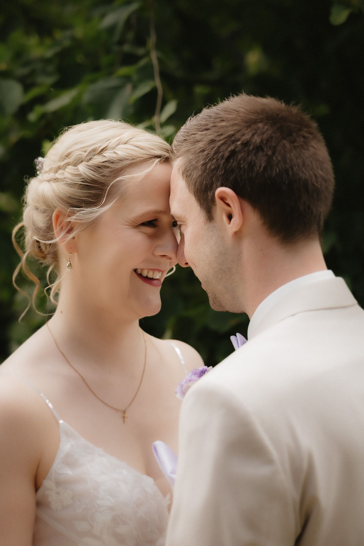 A romantic wedding moment captured outdoors with the couple sharing an intimate moment against a natural green backdrop.