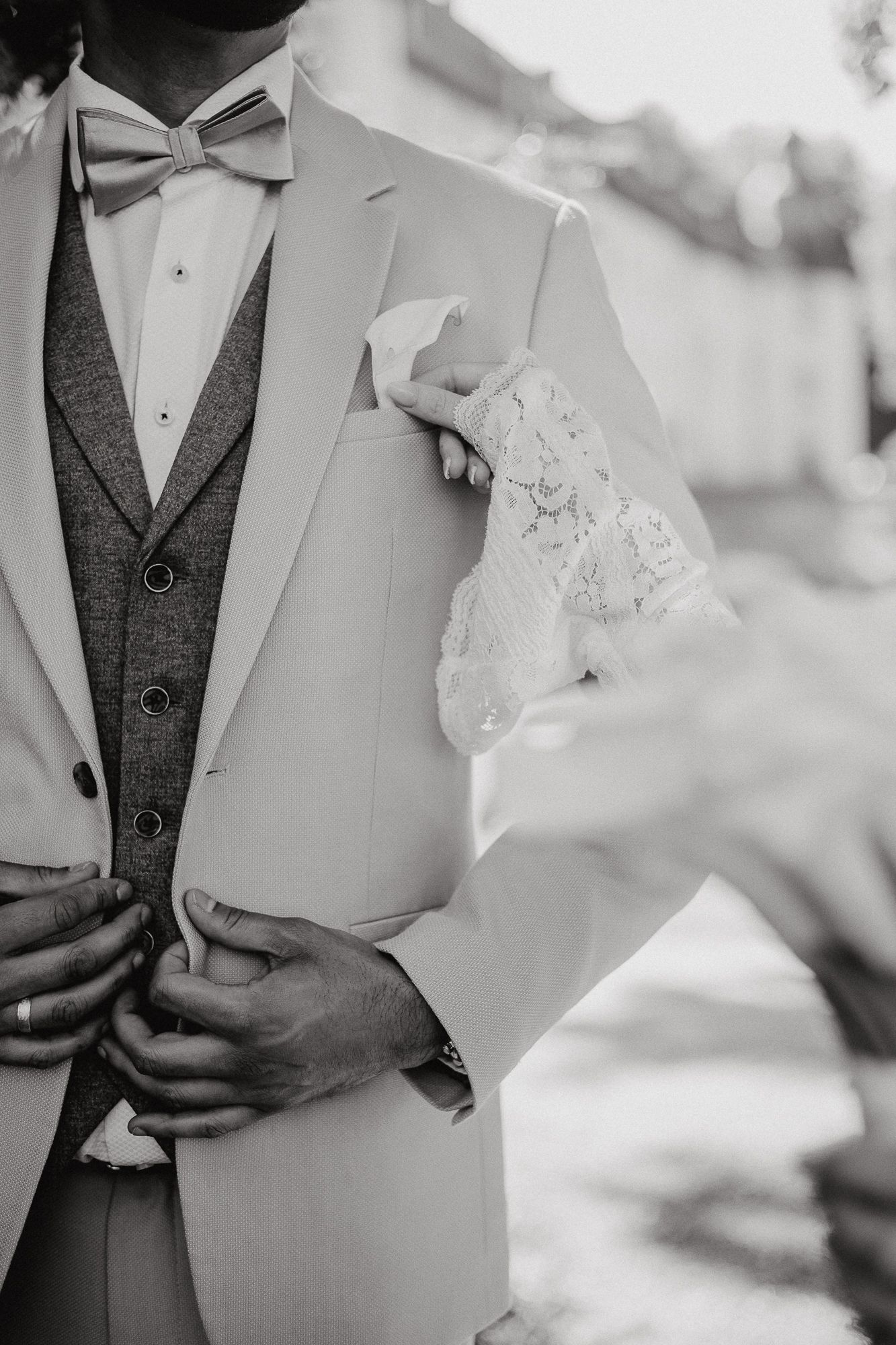 Close-up black and white detail shots of a wedding bouquet with white flowers against formal attire.