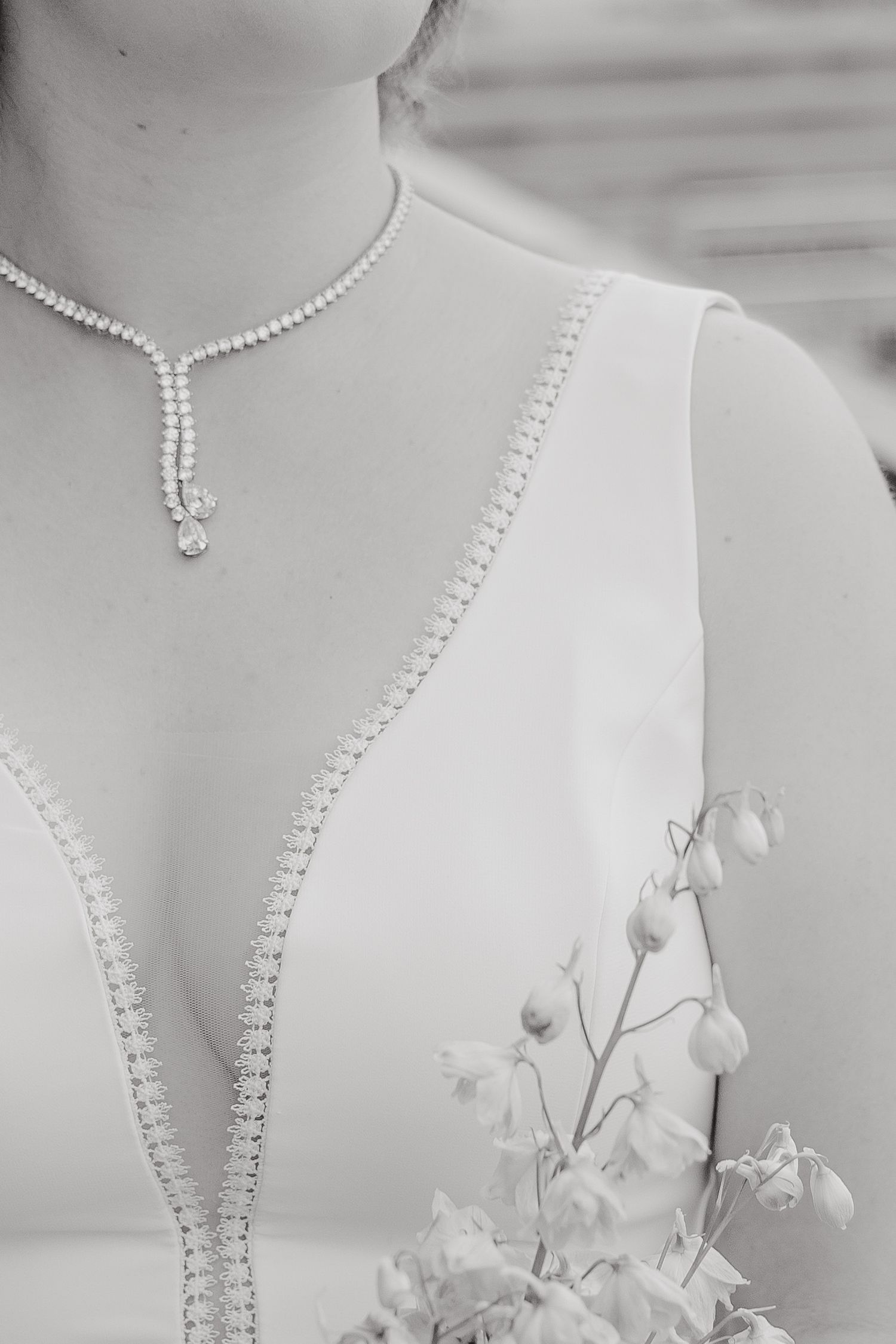 Elegant black and white close-up of a bridal neckline with pearl details and delicate white flowers.